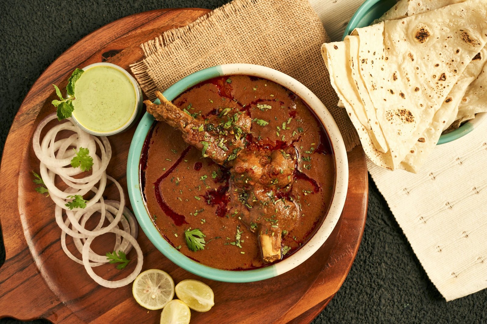 A sumptuous Indian curry served with flatbread and garnished with onions and herbs.
